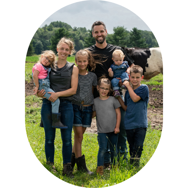 Une famille de producteurs agricoles, dehors avec une vache laitière en arrière plan.