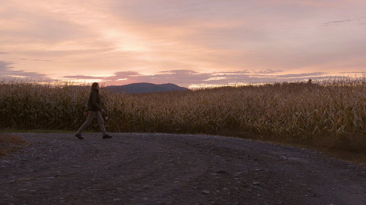 Une productrice marche vers un champ de maïs à l'automne.
