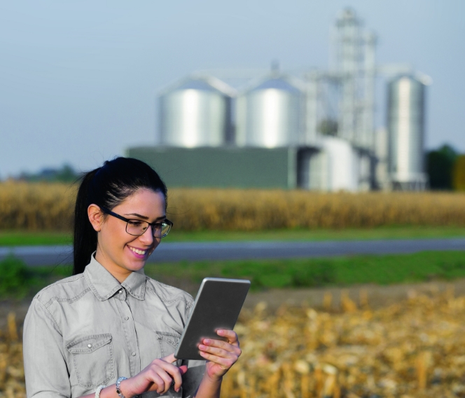 A farmer consults the AgConnexion platform on a tablet in her corn field.