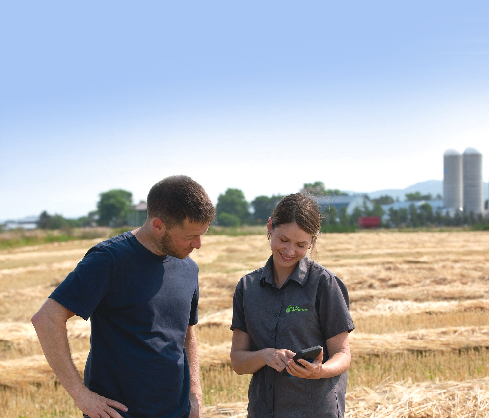 Un agriculteur et une experte Sollio Agriculture consultent l’outil d'agriculture numérique AgConnexion sur un cellulaire.