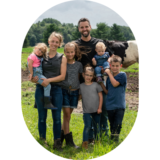 A farming family outside with a dairy cow in the background.