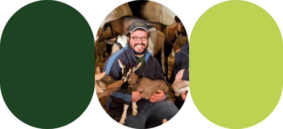 A goat farmer holds a kid in his arms