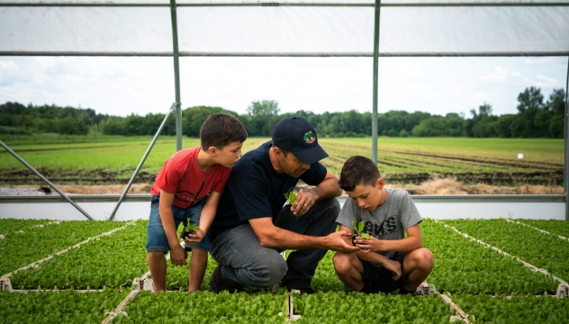 A vegetable producer with his children in a greenhouse.