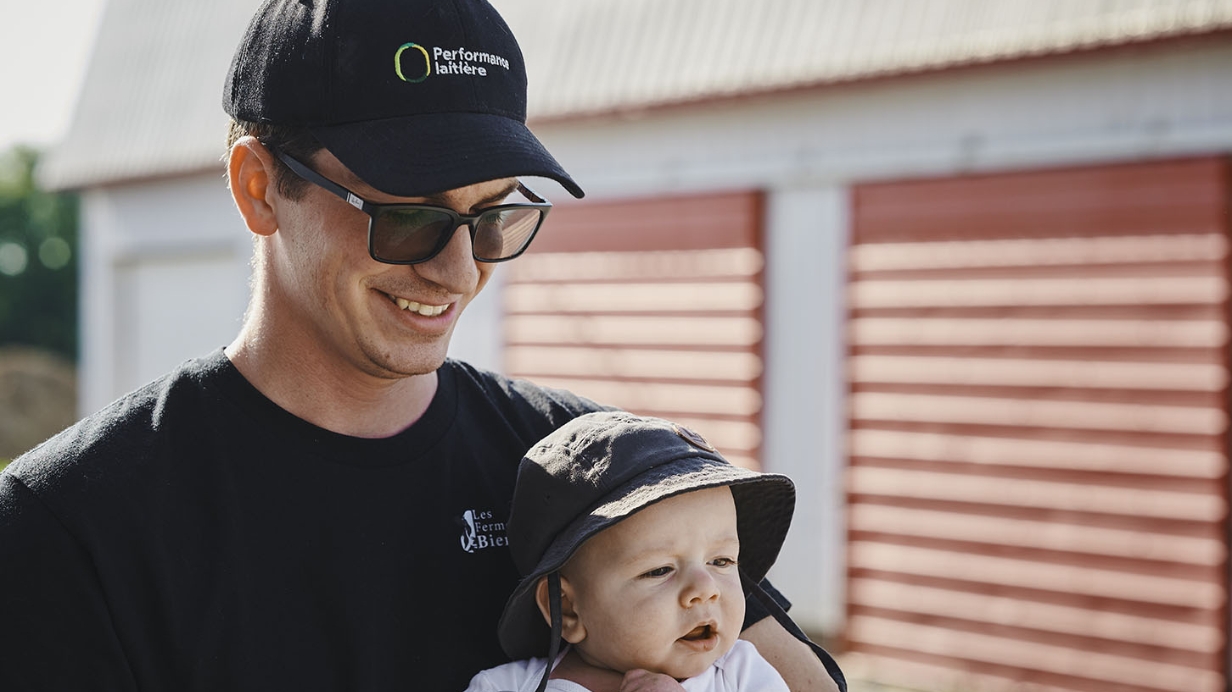 Un récipiendaire du concours Performance laitière pose devant sa ferme avec son bébé. 